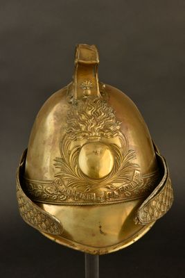 un casque ancien posé sur un socle, sur fond noir