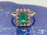 une bague sertie d'une émeraude et de diamants repose sur une pierre bleue