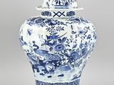 un vase bleu et blanc surmonté d'un oiseau