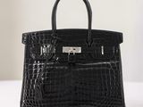 Le sac à main en cuir d'alligator noir est posé sur une table blanche.