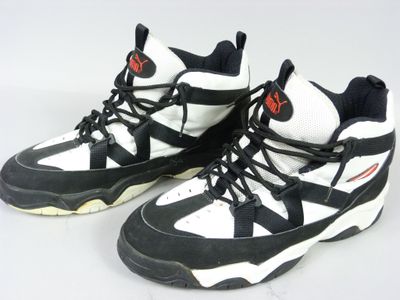 une paire de baskets noires et blanches avec des touches de rouge sur un fond blanc