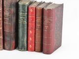 several old books are lined up in a row on a white surface