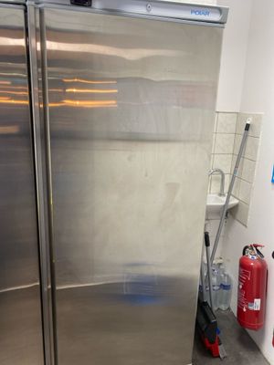 a stainless steel refrigerator in a kitchen with a fire extinguisher