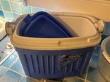 a blue and white trash can sitting on a blue tiled floor