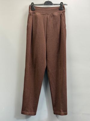 un pantalon marron suspendu à un cintre devant un mur blanc