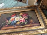 a picture of a painting of flowers in a gold frame on a table
