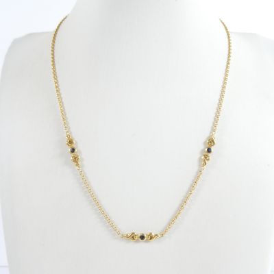 un collier en or orné de pierres noires autour du cou d'un mannequin