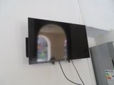 une télévision à écran plat fixée au mur à côté d'un réfrigérateur