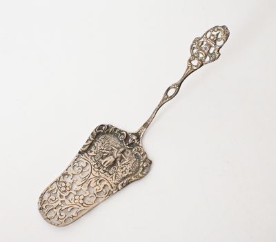 an old silver spoon with a handle on a white surface