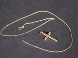 une croix en or avec une chaîne, sur un fond noir