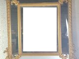 a mirror hanging on the wall with a gold frame
