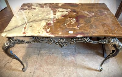 une table en marbre avec un piètement en métal, posée sur un sol carrelé