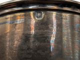 a large metal pot with a handle on a table