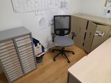 a desk with a chair and a filing cabinet in the corner