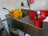 une cuisine avec un évier et de nombreux seaux posés sur le plan de travail
