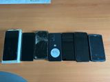 Plusieurs téléphones portables sont posés sur une table, l'écran cassé