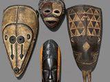 four african masks on a gray surface with a gray background