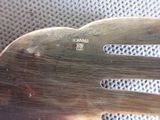 a metal fork with a metal handle sitting on a mesh surface