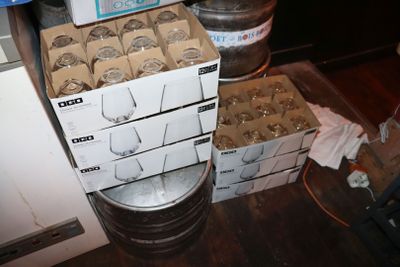 des caisses de bière posées sur un plancher en bois, à côté d'une pile de fûts