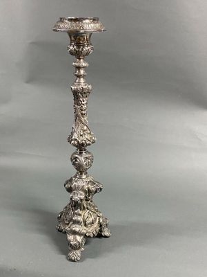an antique silver plated candle holder on a grey background
