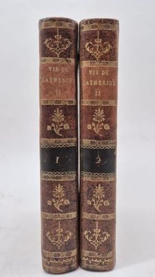 two old books sitting on top of each other on a white surface