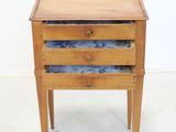 a small wooden table with three drawers on it