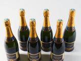 six bottles of champagne are lined up in a row on a white surface