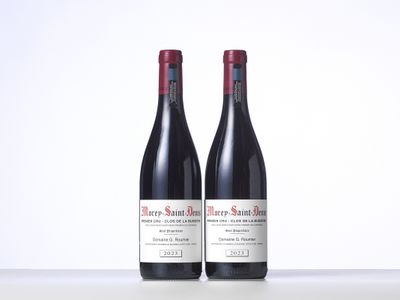 two bottles of red wine sitting on top of a table