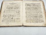 an old book with music notes on it sitting on top of a table