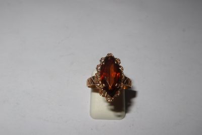 a close up of a ring with an orange stone in it