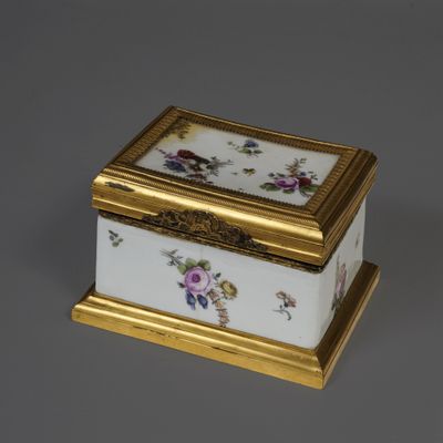 an antique porcelain box with gold trim and flowers on it