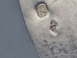 underside view of a silver plate with a skull and cross on it