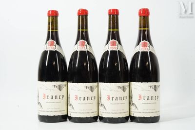 quatre bouteilles de vin rouge sont alignées sur une surface blanche