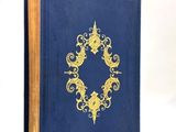 an old blue book with a gold design on the cover