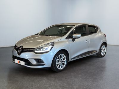 Une voiture argentée est garée dans une pièce aux murs blancs.