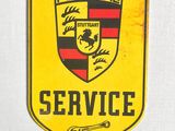 panneau « Porsche Service » jaune et noir accroché à un mur blanc