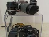 two cameras sitting on a clear shelf next to each other