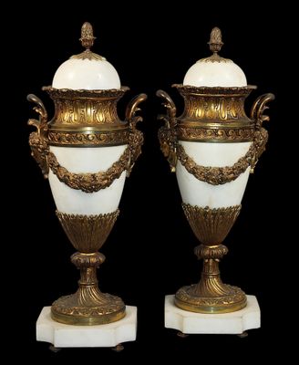 une paire de vases blancs et dorés posés sur des socles en marbre, sur fond noir
