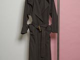 trench coat on a hanger in front of a pink and white wall