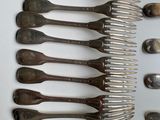 many forks and spoons laid out on a table
