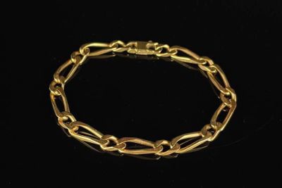 a close up of a gold bracelet on a black background