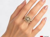 woman ' s hand wearing a gold ring with a cluster of diamonds