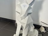 une sculpture blanche représentant un chien assis par terre