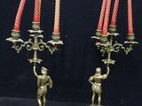 three candles are lit in a brass candle holder with a figurine on the base