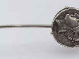 a close up of a silver cuff with a coin on it
