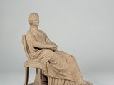 a statue of a man sitting on a bench with his legs crossed