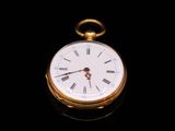 a gold pocket watch with roman numerals on the face