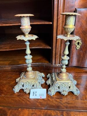 une paire de bougeoirs anciens en laiton exposés devant une bibliothèque
