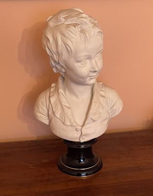 a white bust of a young boy on a wooden table
