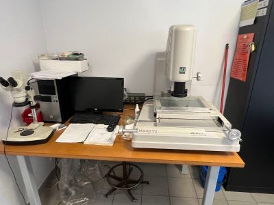 a desk with a microscope, computer, and other items on it